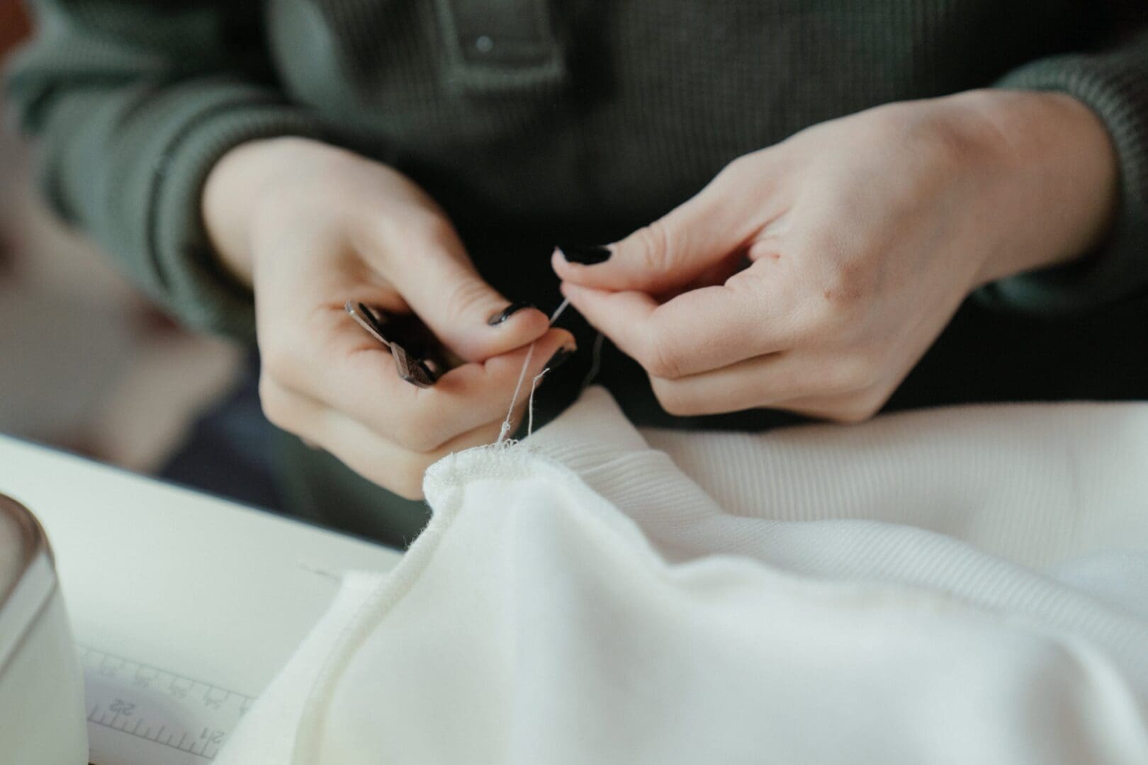 A person sewing something on top of a white sheet.